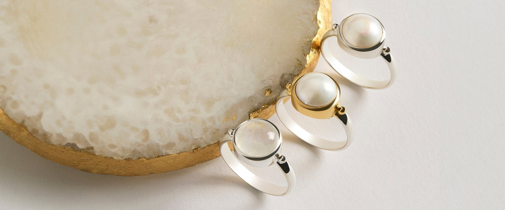 Pearl earrings and necklace on cream background.