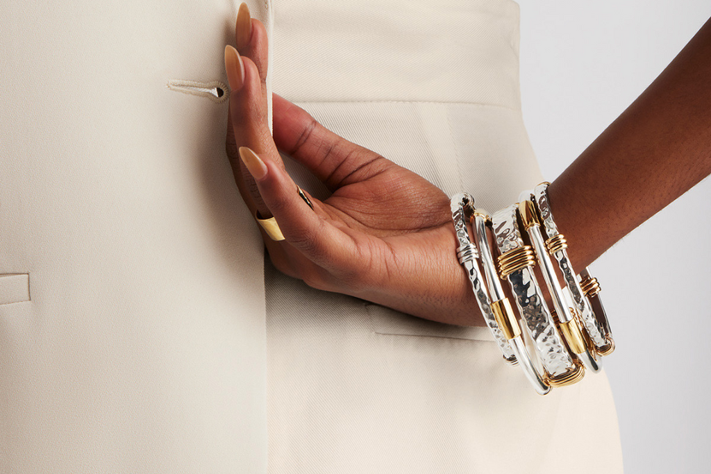 Close up of model wearing five silver and tumbaga bangles and a gold ring